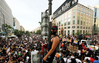 Активист Black Lives Matter на фонарном столбе с указателем перекрестка, названного в честь движения, неподалеку от Белого дома. Вашингтон, федеральный округ Колумбия, 6 июня 2020 года