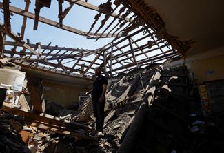 Житель Макеевки Аран стоит среди руин своего магазина, разрушенного недавним обстрелом