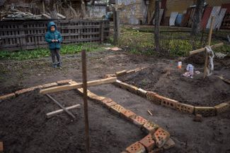 Шестилетний мальчик смотрит на могилу своей матери, умершей от голода, во дворе их дома в Буче