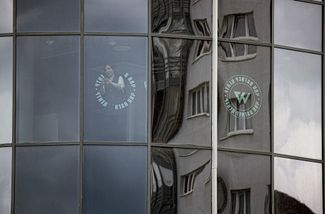 Женщина оттирает логотип ЧВК Вагнера с окон бизнес-центра «Морская столица», где компания Евгения Пригожина арендовала несколько этажей
