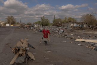 Жительница села Ясенового, к югу от Покровска, собирает доски на месте разрушенных обстрелами построек, чтобы топить ими свой дом. 8 октября 2024 года