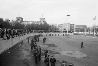 Пограничники ГДР наблюдают за толпами людей, отмечающих открытие Берлинской стены. 10 ноября 1989 года