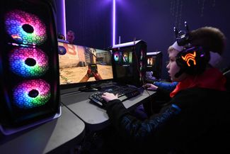 A boy plays a first-person shooter video game in the Russian Defense Ministry’s pavilion at the All-Russian Exhibition Center
