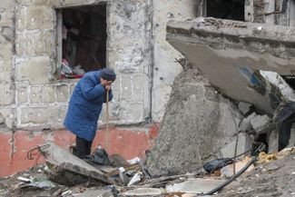 Жительница Бородянки Киевской области плачет, пытаясь найти своего сына под обломками жилого дома.