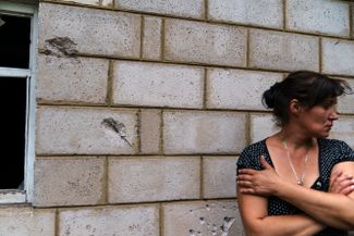 Жительница Краматорска Ольга Гурина стоит у поврежденной шрапнелью стены дома