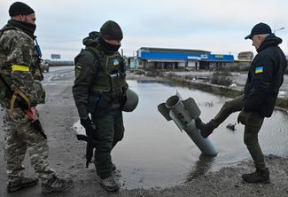 Игорь Дударь (справа) и украинские военные осматривают обломки ракеты из асфальта