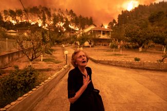 Жительница острова Эвбея перед своей горящей деревней. 8 августа 2021 года