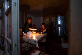 A woman and her son have dinner by candlelight at their home in Stepanakert. January 18, 2023.