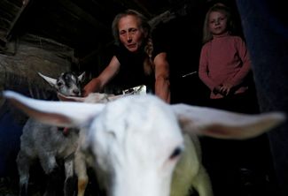 Артистка цирка Лилия Чернова и ее дочь Александра проверяют коз в сарае возле своего дома во время боев в округе. Попасная, Луганская область