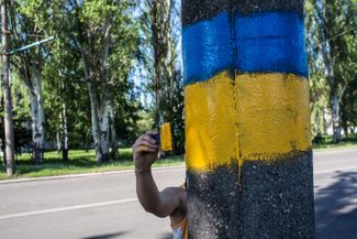 A man paints the colors of the Ukrainian flag on a lamp post in Dobropillya, Donetsk region. May 21, 2014.