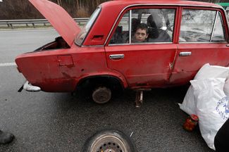 Мальчик ждет в машине, пока родители меняют колесо. Эта семья покидает Дмитровку — село в Киевской области, на днях перешедшее под контроль украинских войск