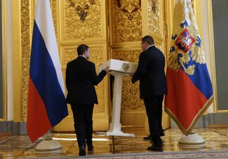 Сотрудники протокола выносят трибуну перед встречей Владимира Путина с доверенными лицами. Кремль, 20 марта 2024 года