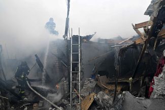 Украинские пожарные тушат огонь в одном из разрушенных жилых домов