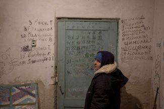Женщина в подвале села Ягодное под Черниговом, пережившем оккупацию российскими военными. В подвале жители Ягодного прятались от обстрелов. Слева на стене написаны имена убитых российскими военными, справа — погибших от тяжелых условий
