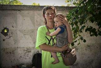 Мать с ребенком ждут эвакуационного автобуса из Лисичанска.