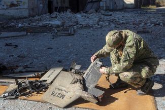 A Ukrainian police officer examines the ruins of a Shahed 136 kamikaze drone.
