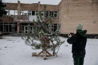 Житель прифронтового города Гуляйполе Запорожской области фотографирует елку