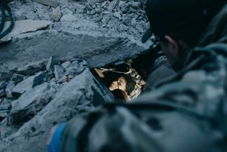 Спасатель смотрит на жительницу Краматорска, находящуюся под завалами