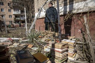 Житель попавшего под удар дома в Краматорске выносит книги из своей квартиры