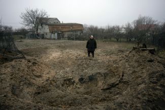 Жительница Киева у воронки от снаряда на заднем дворе ее дома на окраине города