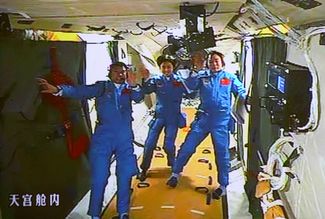 На этом снимке, сделанном с экрана монитора в Пекинском Аэрокосмическом центре управления полетами и выпущенном китайским информационным агентством «Синьхуа», китайские астронавты, слева, Лю Ван, Лю Ян И Цзин Хайпэн плывут в орбитальном лабораторном модуле «Тяньгун-1».