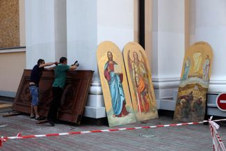 Workers at the Transfiguration Cathedral with a decoration that survived Russia’s July 24 attack