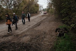 Жители Кирилловки идут мимо тела погибшего российского солдата