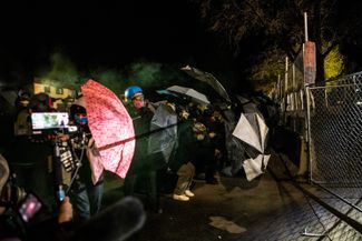 Демонстранты защищаются зонтиками от перечных и слезоточивых зарядов, которыми их обстреливает полиция по время акции протеста против убийства Донте Райта. Бруклин-Сентер, штат Миннесота, 16 апреля 2021 года. 