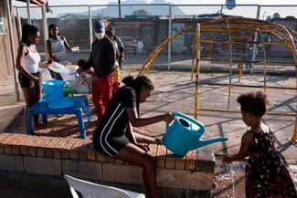 Девочка моет руки в детском саду в пригороде Кейптауна, 14 мая 2020 года