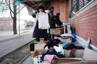 Жители ищут подходящую одежду в пункте раздачи гуманитарной помощи. 