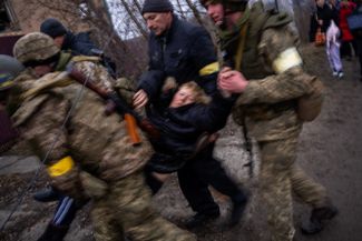 Украинские военные переносят женщину через реку Ирпень во время эвакуации жителей на окраине Киева