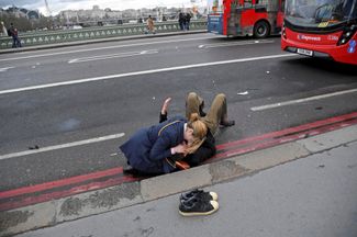 Женщина оказывает помощь пострадавшему при теракте на Вестминстерском мосту. Лондон, 22 марта