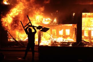 Демонстрант на фоне горящего здания. Миннеаполис, штат Миннесота, 29 мая 2020 года