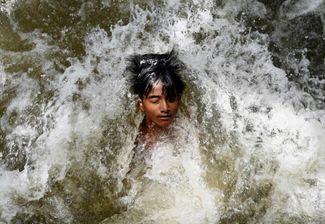 Спасаясь от жары, ребенок в индийском Дели охлаждается в канализационных водах