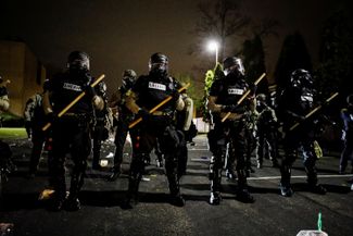 Полицейские обороняют отделение полиции города Бруклин-Сентр штата Миннесота от демонстрантов, которые проводят акцию протеста против убийства афроамериканца при задержании. 11 апреля 2021 года