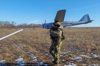 Военнослужащий ВС РФ несет разведывательный дрон самолетного типа «Орлан-10», район города Лимана (Красного Лимана). 16 февраля 2024 года