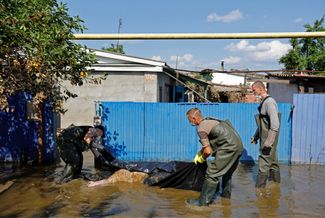 Работники окоммунальных служб выносят из затопленного дома тело погибшего жителя города Голая Пристань в 90 километрах от Новой Каховки. 16 июня 2023 года