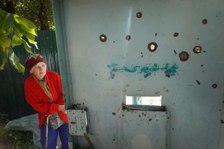Жительница Славянска у ворот своего дома, поврежденных в результате обстрела кассетными боеприпасами