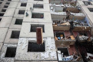 Жители Киева выбрасывают мебель из окна разрушенного многоэтажного дома