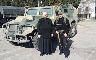 Father Dimitry in front of an armored vehicle. March 2014.