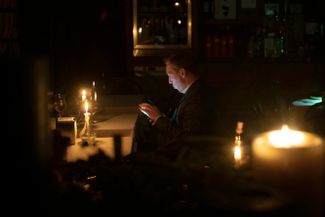 Мужчина сидит в киевском кафе во время отключения света, затронувшего значительную часть города