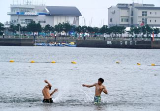 Люди купаются возле яхтенной гавани Эносима — одного из объектов Олимпиады в Токио, 14 июля 2021 года.