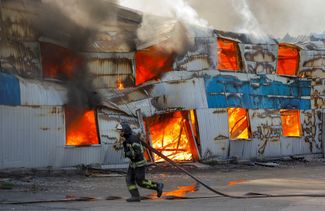 Пожарный тушит огонь в типографии в Кировском районе Донецка, загоревшейся после обстрела. Власти самопровозглашенной ДНР сообщили о двух погибших