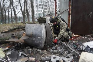 Украинский полицейский осматривает обломок ракеты, упавшей рядом с жилым домом в Харькове