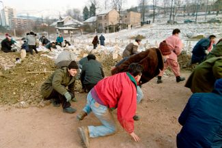 Жители Сараева во время минометного обстрела кладбища, где проходят похороны одного из погибших в гражданской войне. Декабрь 1992 года