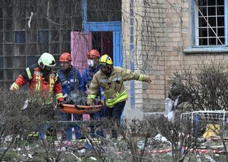 Спасатели выносят тело погибшего из одного из зданий Ржищева, разрушенного российской ракетой