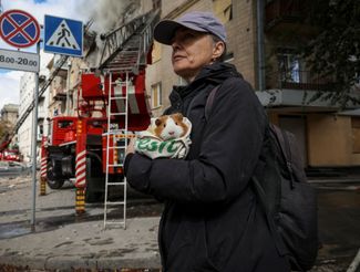 Жительница Харькова Оксана Кошнарева держит в руках свою морскую свинку Ириску, стоя возле своего жилого дома, разрушенного из-за ракетного удара