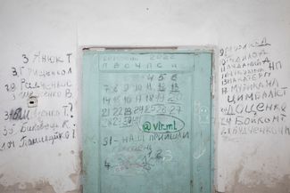 A school basement in the village of Yahidne, Chernihiv region, where more than 300 residents spent 28 days without electricity, heat, or fresh air. To the left of the door are the names of people who had been killed by the Russian military; to the right, the names of those who died in the basement. The last entry in the log of their confinement reads: “31 — our troops have come.”