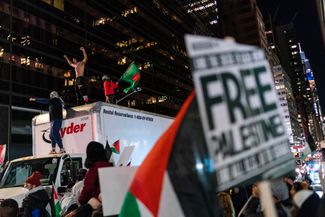 Демонстранты, требующие немедленного прекращения огня в секторе Газа, забрались на грузовик во время марша в Нью-Йорке. 10 ноября