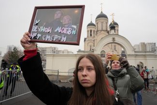 A mourner holds up a photo of Navalny and his widow, Yulia, with the words “Eternal love never dies” taped onto it.